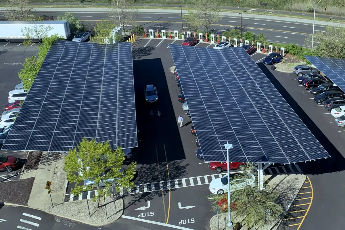 Carros estacionados sob carports solares abertos, com os módulos fotovoltaicos formando o teto das vagas